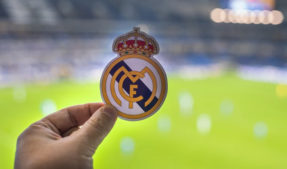 Real Madrid-logo met een voetbalveld op de achtergrond